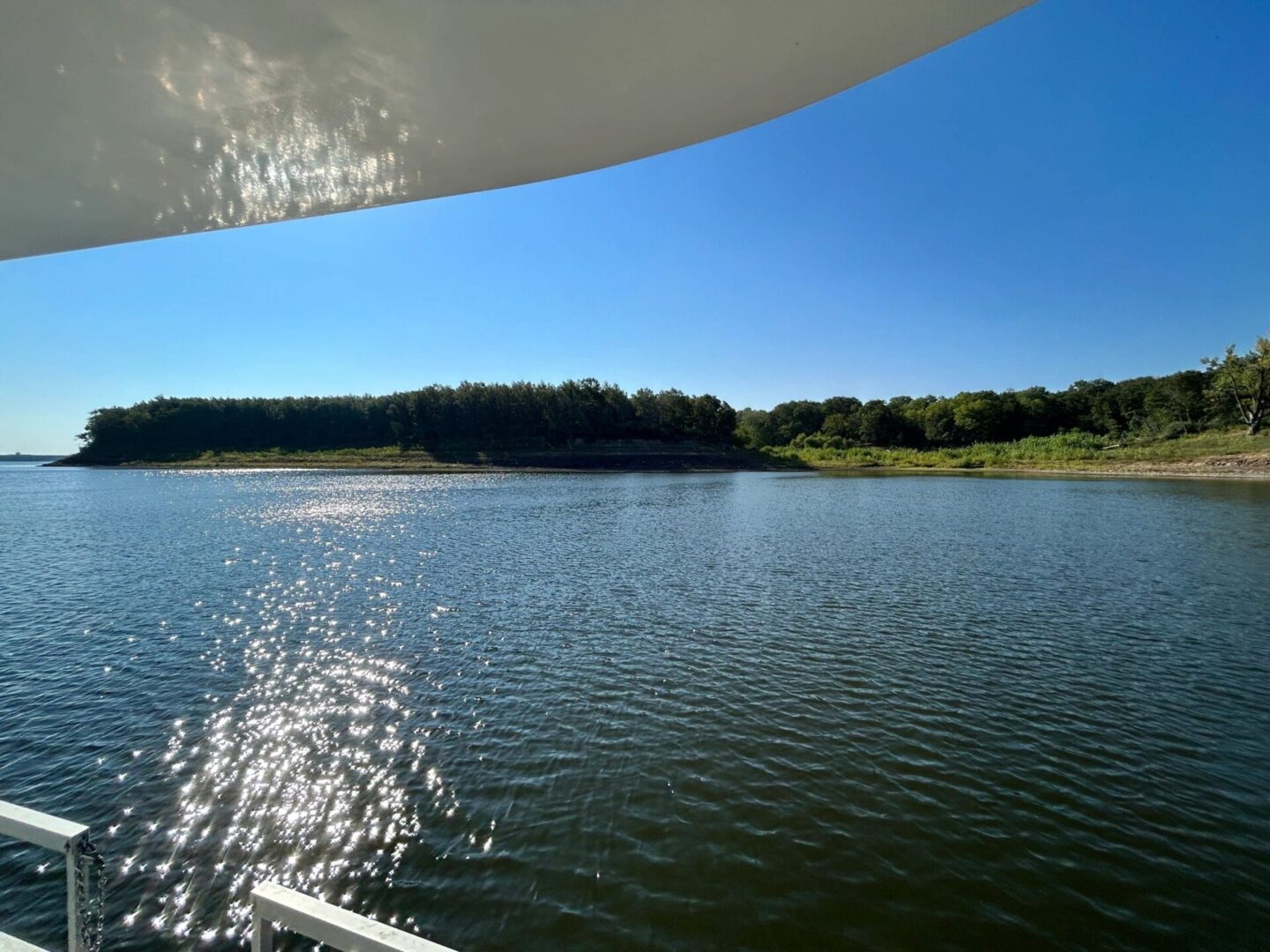 A boat is sailing on the water near some trees.