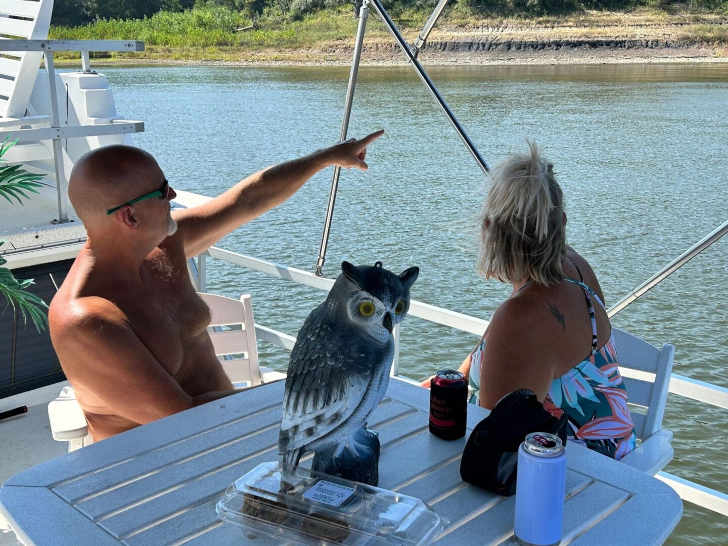 A man and woman sitting at the table with an owl.