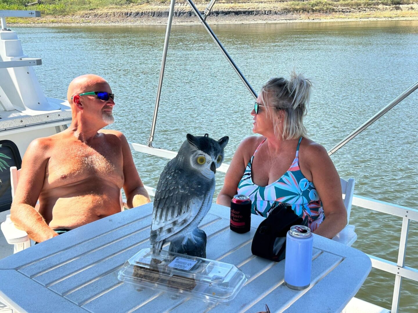 A man and woman sitting at a table with an owl on it.