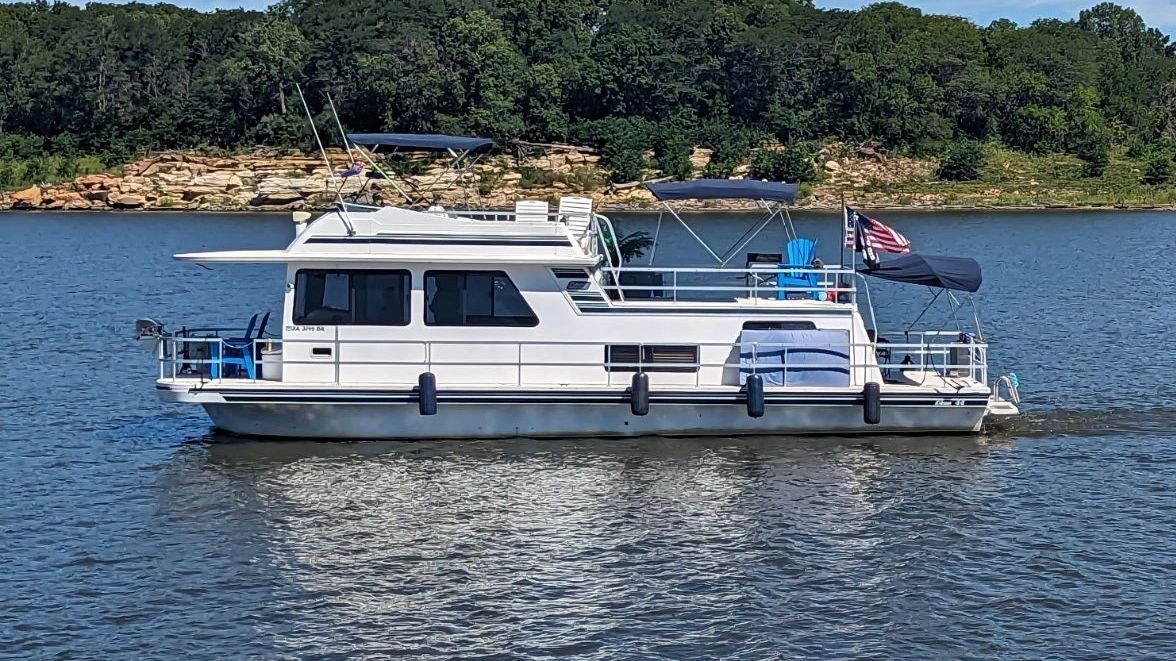 A white boat is in the water near some trees.