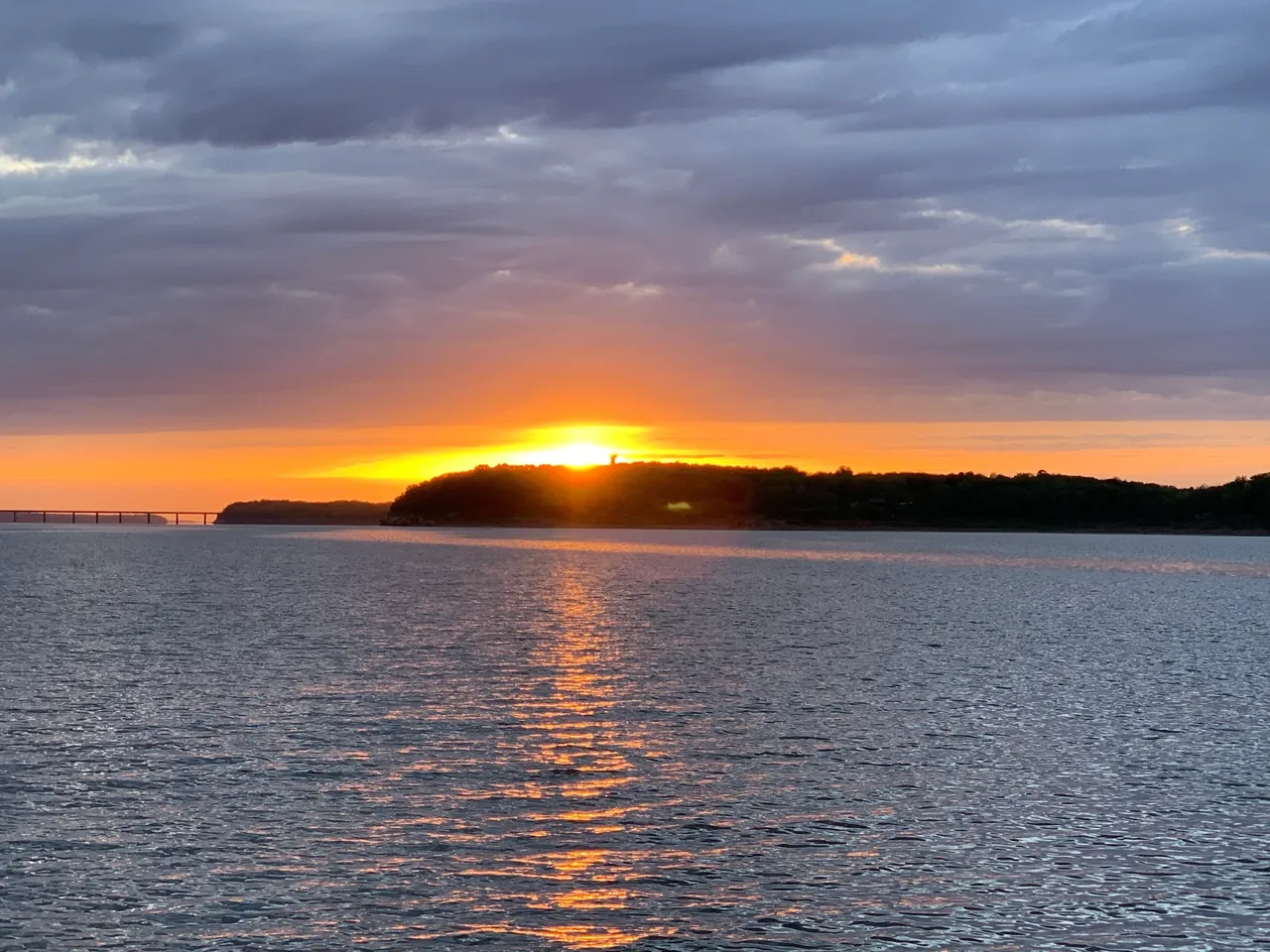 A sunset over the ocean with clouds in the sky.