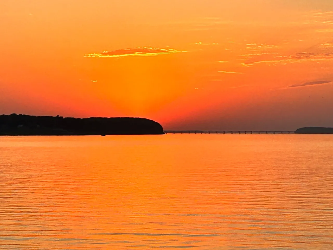 A sunset over the ocean with an island in the distance.