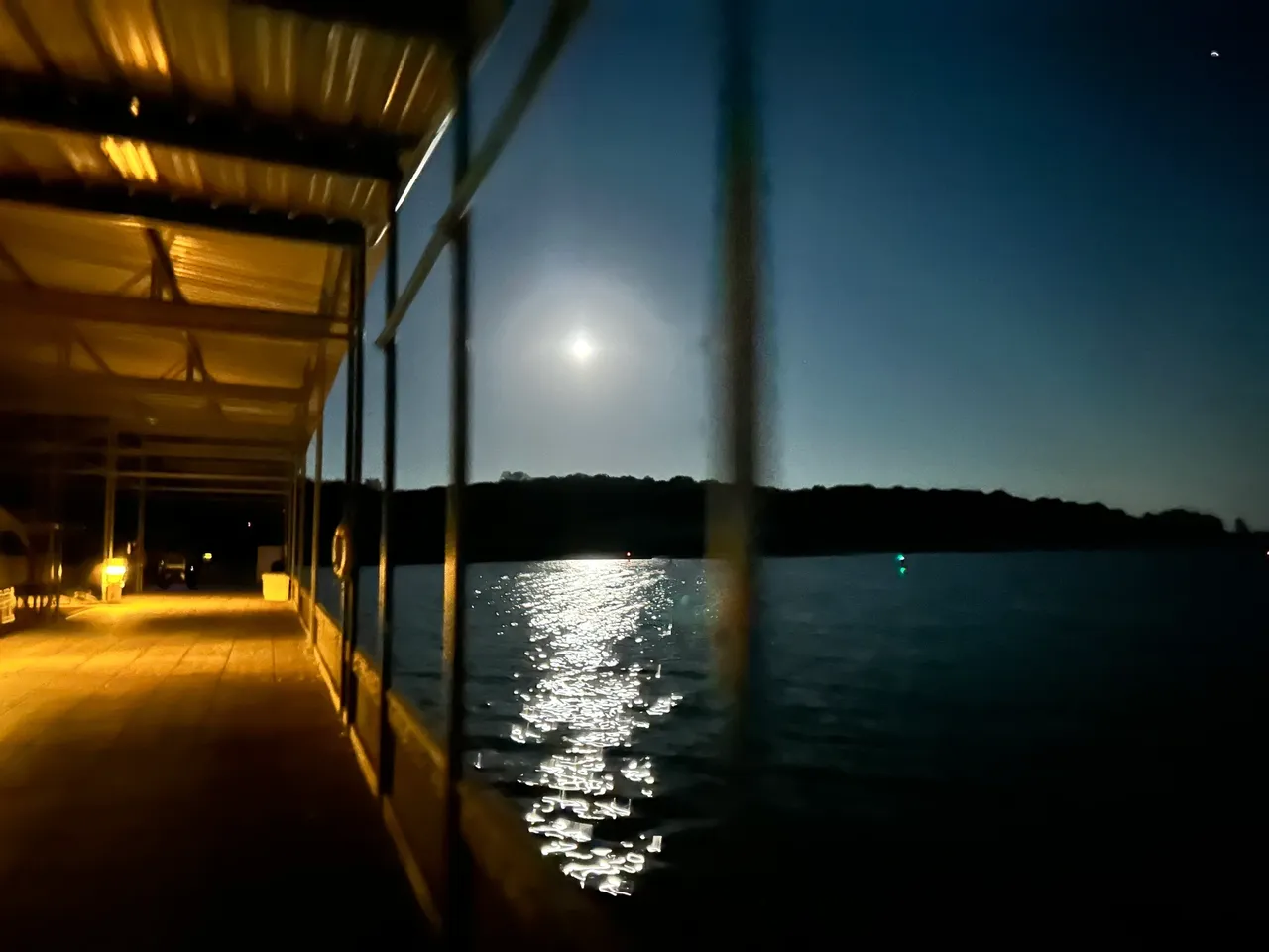 A dock with the moon setting in the background.