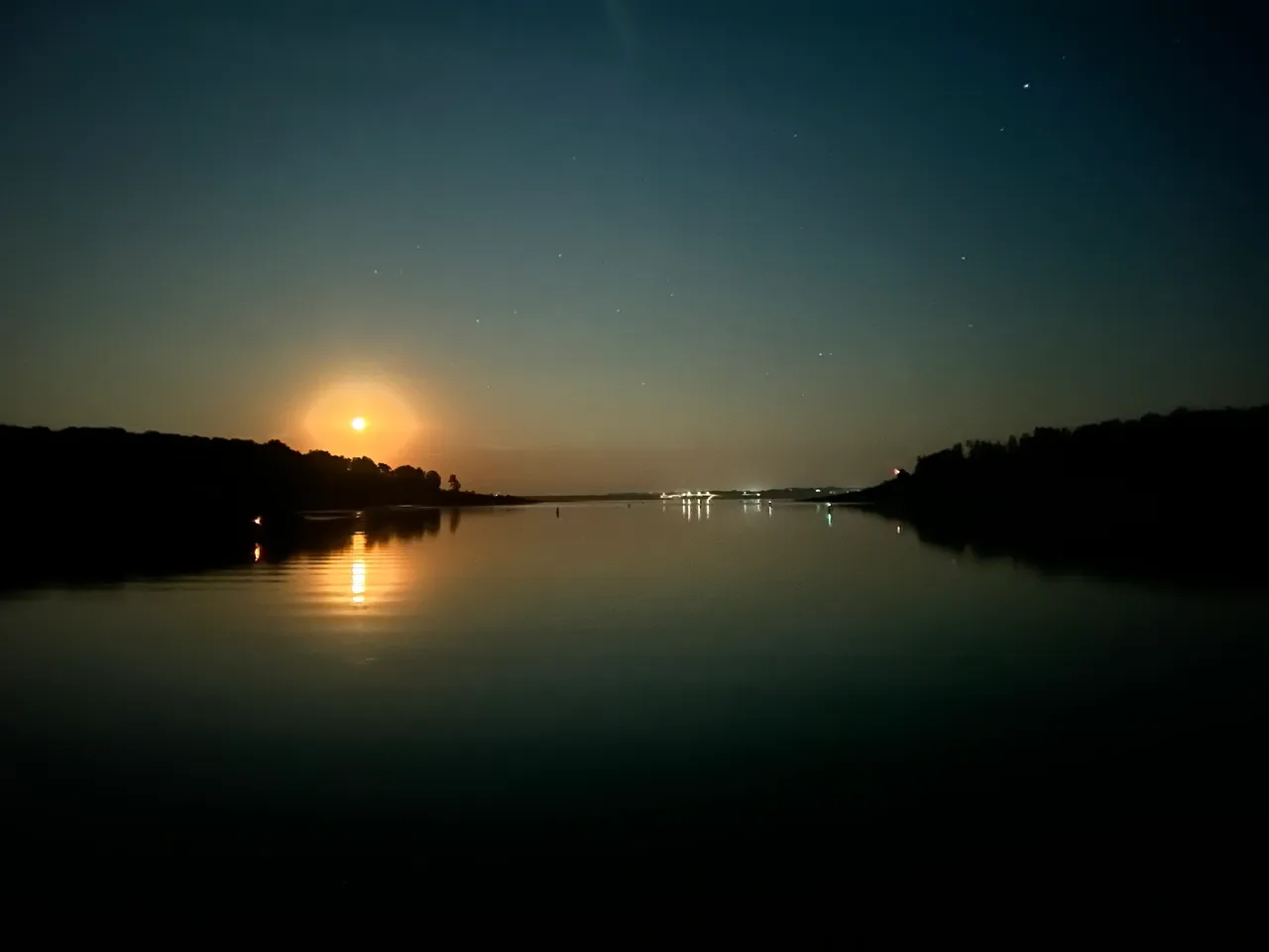 A body of water with the sun setting in the distance.