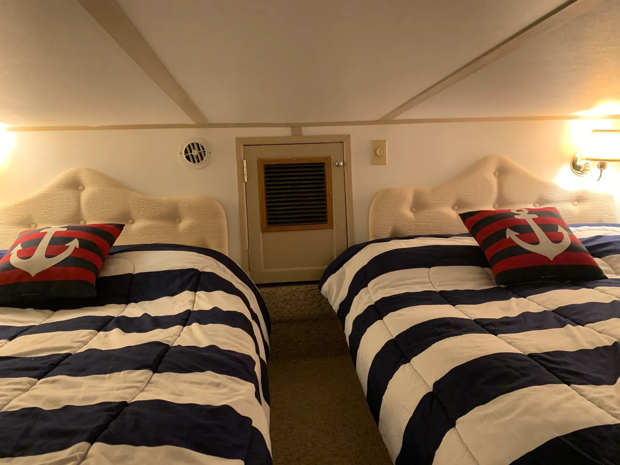 Two beds in a room with striped blankets.