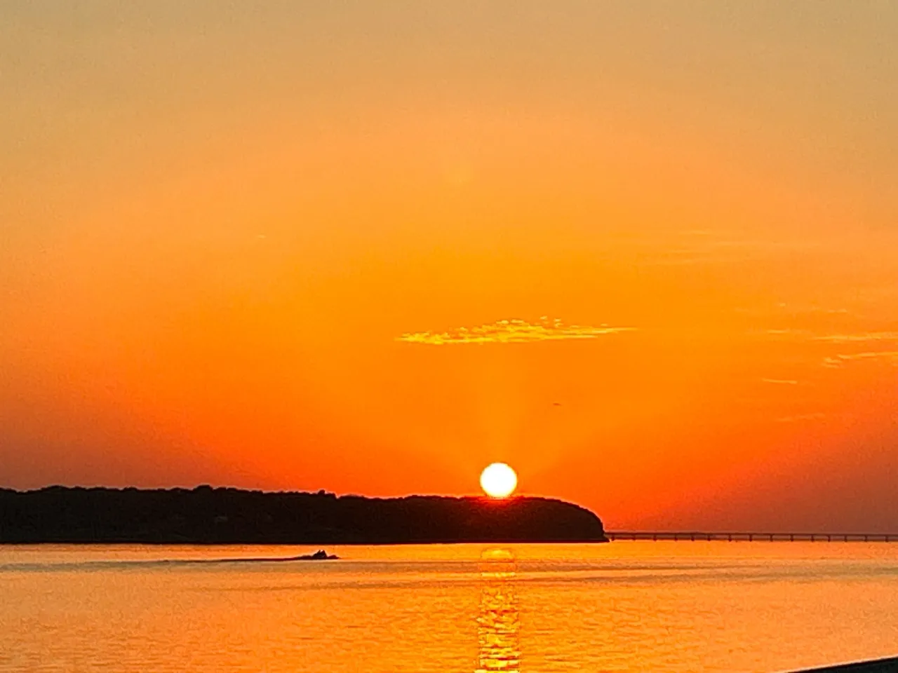 A sunset over the ocean with a boat in it.